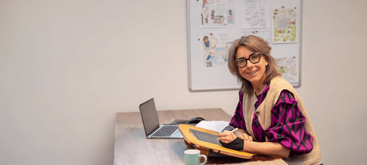 Annemarie Jager aan het werk met laptop, notitieblok en whiteboard vol zakelijke illustraties en procesnotities voor tekst in Deventer. Wil jij dit ook?